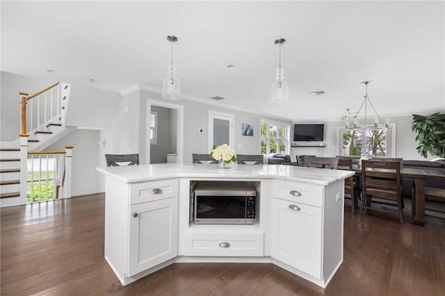 36 Wanda St, Narragansett, RI 02882 - kitchen featuring stainless steel microwave, crown molding, white cabinets, hanging light fixtures, and dark wood-style floors