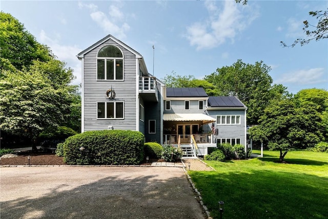 48 Wright Ln, Jamestown, RI 02835 - view of front facade featuring a front lawn, roof mounted solar panels, metal roof, a porch, and a standing seam roof