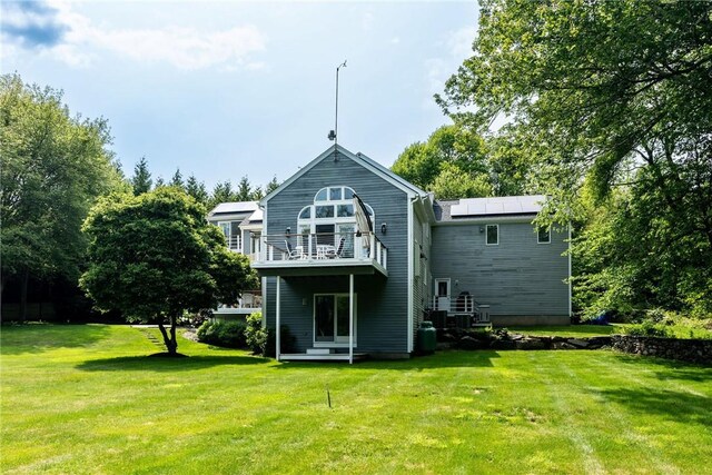 48 Wright Ln, Jamestown, RI 02835 - back of house with a balcony, a lawn, and roof mounted solar panels