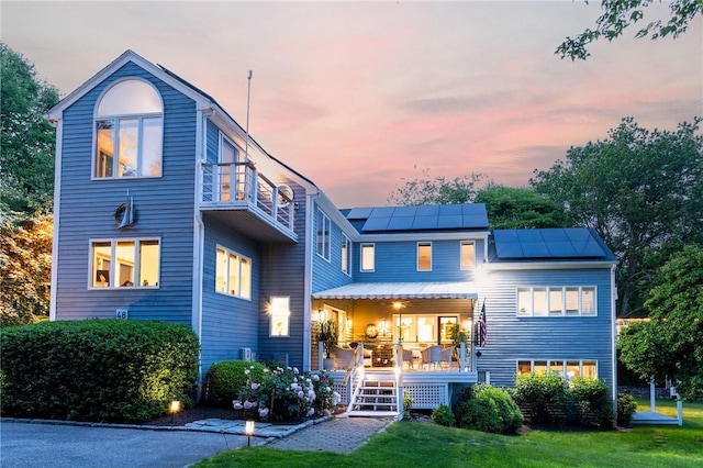 48 Wright Ln, Jamestown, RI 02835 - back of house at dusk with solar panels, covered porch, and a balcony