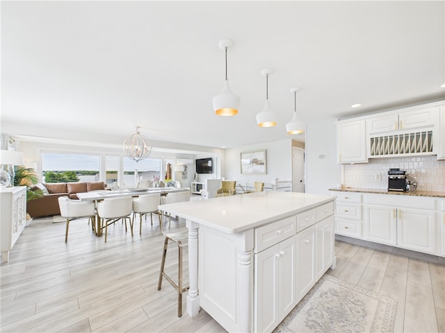 6 Dolphin Rd, Narragansett, RI 02882 - kitchen featuring light wood-style floors, decorative backsplash, light countertops, a chandelier, and white cabinets