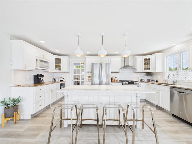 6 Dolphin Rd, Narragansett, RI 02882 - kitchen featuring appliances with stainless steel finishes, wall chimney range hood, a sink, backsplash, and a center island