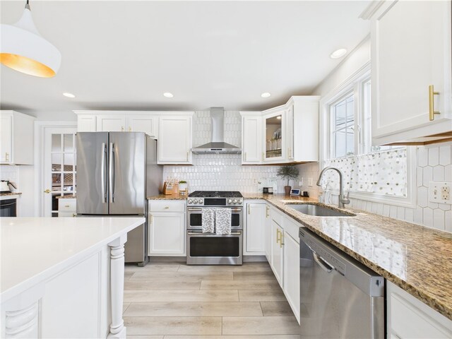 6 Dolphin Rd, Narragansett, RI 02882 - kitchen featuring wall chimney exhaust hood, stainless steel appliances, a sink, white cabinetry, and tasteful backsplash