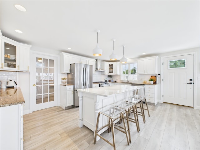 6 Dolphin Rd, Narragansett, RI 02882 - kitchen with appliances with stainless steel finishes, light wood-style flooring, wall chimney exhaust hood, backsplash, and recessed lighting