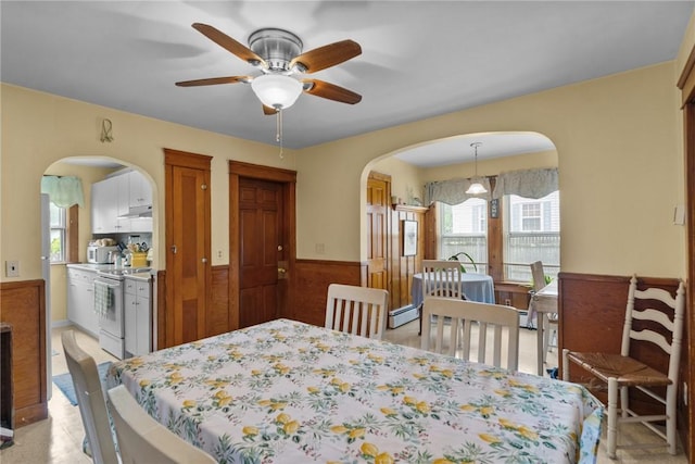 99 Third St, West Warwick, RI 02893 - dining area featuring arched walkways, a wainscoted wall, a ceiling fan, and a baseboard radiator