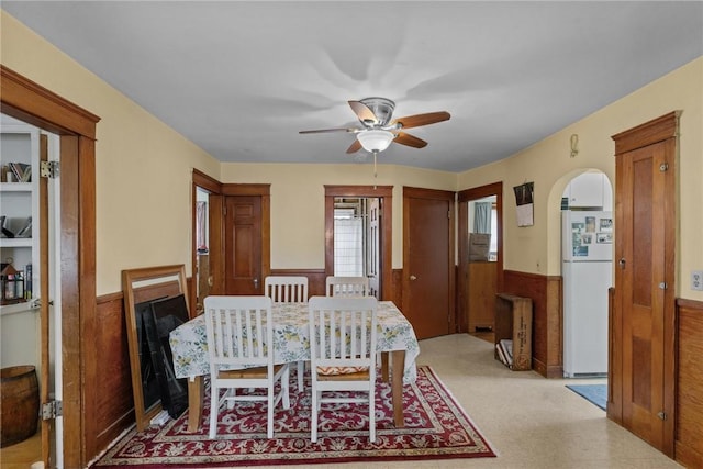 99 Third St, West Warwick, RI 02893 - dining room featuring wainscoting, a ceiling fan, wooden walls, and arched walkways