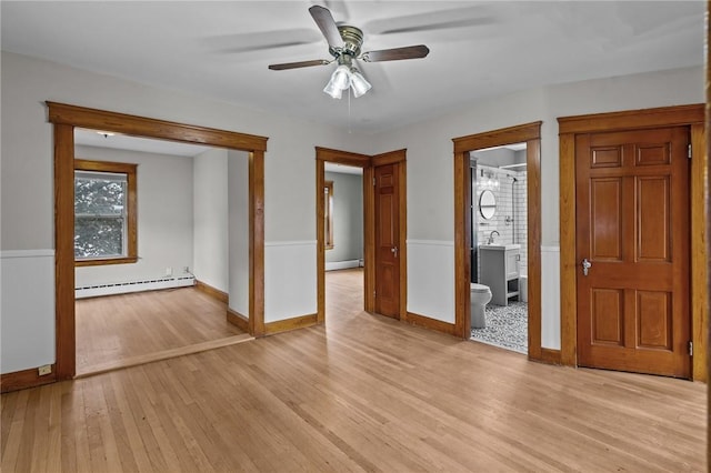 99 Third St, West Warwick, RI 02893 - unfurnished room with a baseboard heating unit, light wood-style floors, baseboard heating, a ceiling fan, and a wainscoted wall