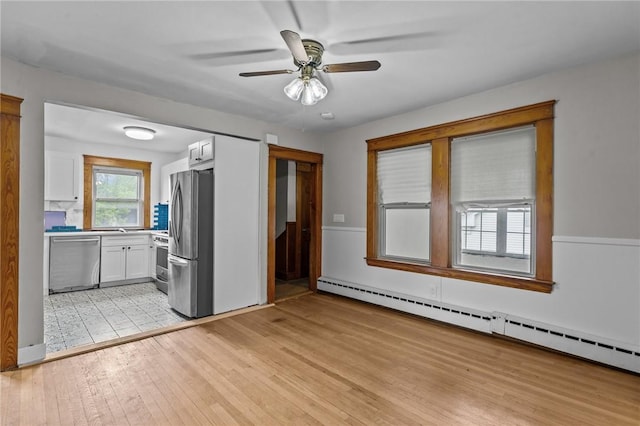 99 Third St, West Warwick, RI 02893 - kitchen with stainless steel appliances, white cabinets, a baseboard radiator, light wood-style flooring, and ceiling fan