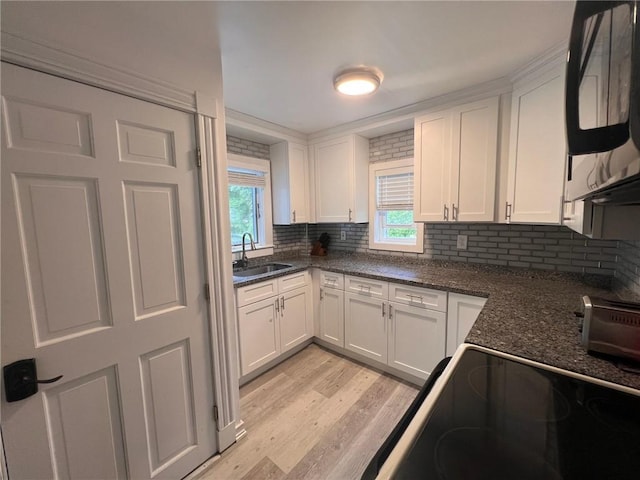 3506 Kingstown Rd, South Kingstown, RI 02892 - kitchen featuring a sink, black microwave, white cabinetry, light wood-style floors, and decorative backsplash
