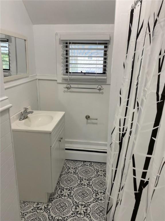 3506 Kingstown Rd, South Kingstown, RI 02892 - full bath with vanity, plenty of natural light, baseboard heating, wainscoting, and tile patterned floors