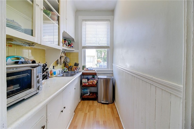 93 Naples Ave, Providence, RI 02908 - kitchen with a sink, light wood-type flooring, white cabinetry, a wainscoted wall, and light countertops