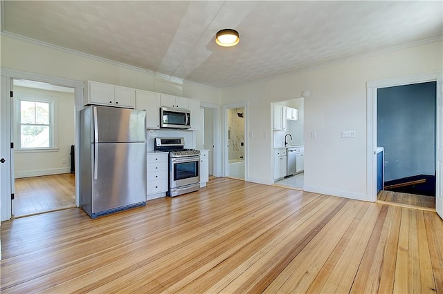 93 Naples Ave, Providence, RI 02908 - kitchen featuring appliances with stainless steel finishes, light wood finished floors, white cabinets, ornamental molding, and baseboards