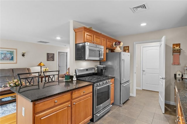 5 Leighas Ln, Coventry, RI 02816 - kitchen with stainless steel appliances, dark stone counters, light tile patterned flooring, recessed lighting, and brown cabinetry