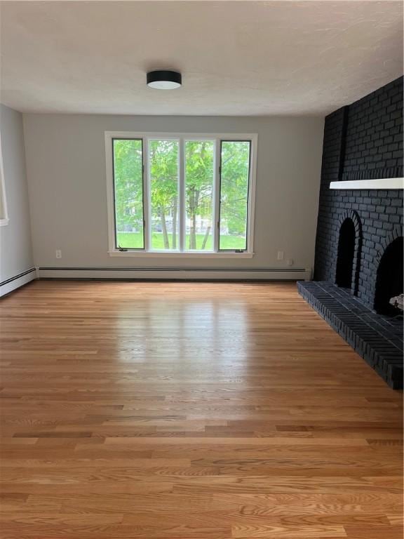 62 Lucille Dr, Woonsocket, RI 02895 - unfurnished living room with light wood-type flooring and a brick fireplace