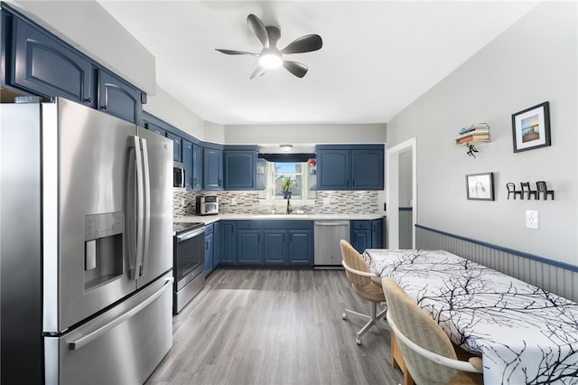 39 Camac St, Pawtucket, RI 02861 - kitchen with stainless steel appliances, blue cabinets, light countertops, backsplash, and a ceiling fan