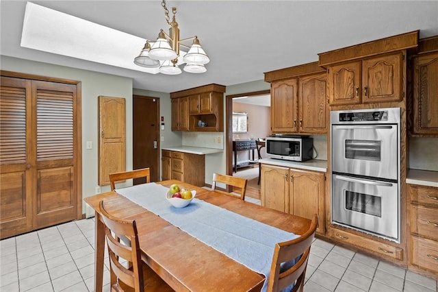 15 Womantam Ln, Cumberland, RI 02864 - kitchen featuring stainless steel appliances, light tile patterned flooring, a chandelier, brown cabinetry, and light countertops