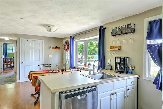 92 Chatworth Ave, Warwick, RI 02886 - kitchen featuring dishwasher, a sink, light countertops, wood finished floors, and white cabinets