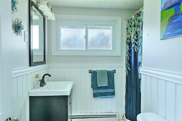 92 Chatworth Ave, Warwick, RI 02886 - full bath featuring a baseboard heating unit, vanity, wainscoting, toilet, and curtained shower