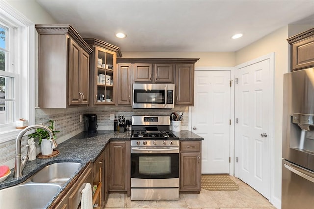 1710 Phenix Ave, Cranston, RI 02921 - kitchen featuring stainless steel appliances, a sink, backsplash, glass insert cabinets, and dark stone counters