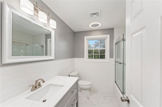 1710 Phenix Ave, Cranston, RI 02921 - bathroom featuring vanity, marble look tile flooring, toilet, tile walls, and enclosed tub / shower combo