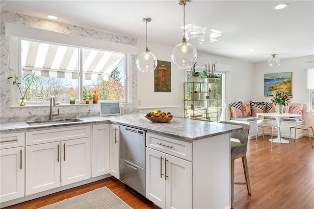 7 Maloney Ln, Middletown, RI 02842 - kitchen with a sink, dishwasher, white cabinetry, wood finished floors, and a peninsula