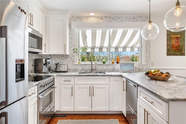 7 Maloney Ln, Middletown, RI 02842 - kitchen featuring appliances with stainless steel finishes, a sink, a peninsula, white cabinets, and pendant lighting