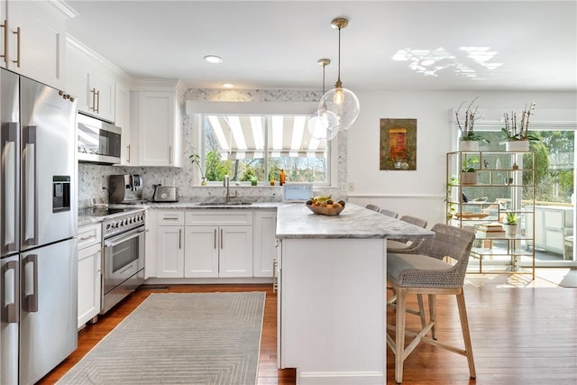 7 Maloney Ln, Middletown, RI 02842 - kitchen featuring appliances with stainless steel finishes, a sink, a center island, dark wood-type flooring, and a wainscoted wall