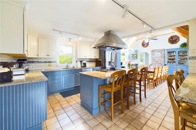 1087 Lakeside Dr, Block Island, RI 02807 - kitchen featuring track lighting, island range hood, a sink, light tile patterned floors, and decorative backsplash