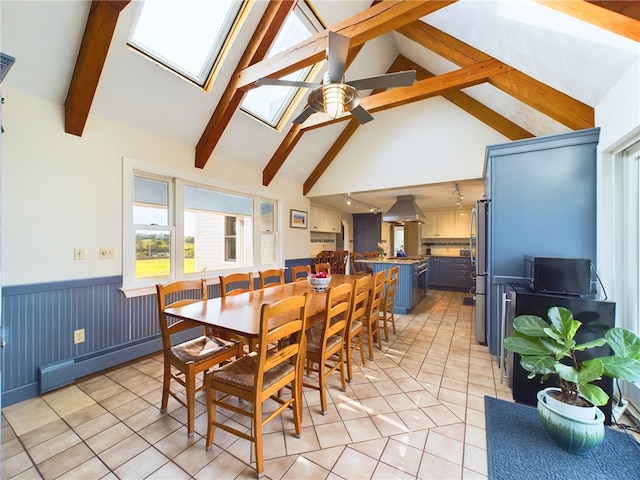 1087 Lakeside Dr, Block Island, RI 02807 - dining space with light tile patterned floors, ceiling fan, a wainscoted wall, a skylight, and a baseboard heating unit