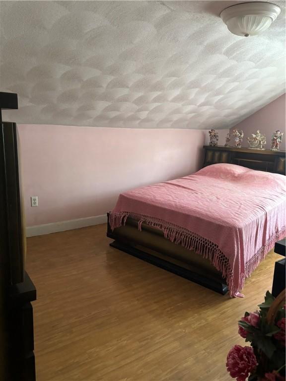 259 Park Ave, Woonsocket, RI 02895 - bedroom featuring lofted ceiling, a textured ceiling, wood finished floors, and baseboards
