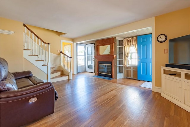 369 Vine St, Pawtucket, RI 02861 - living area featuring wood finished floors, a fireplace with flush hearth, stairs, and radiator heating unit