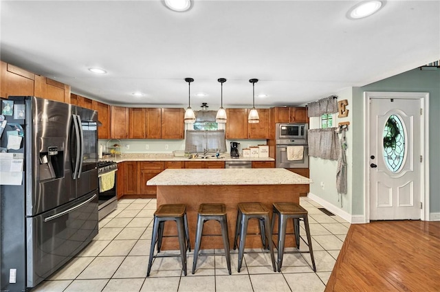 69 Arnold St, Lincoln, RI 02865 - kitchen with stainless steel appliances, a kitchen bar, brown cabinetry, light tile patterned floors, and a sink