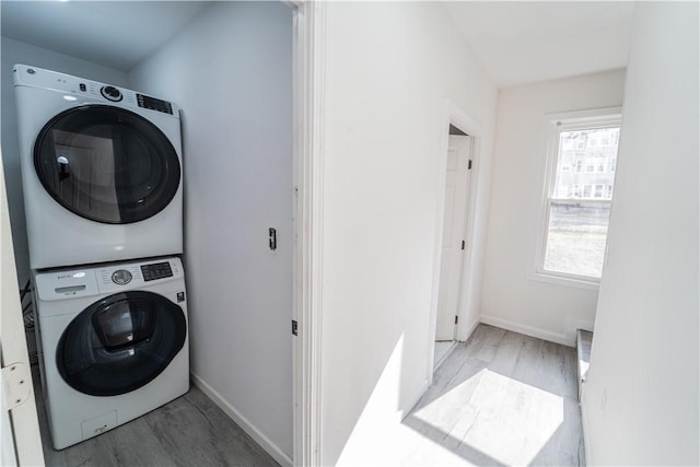 132 Chestnut St, Woonsocket, RI 02895 - laundry area featuring estacked washer and dryer, wood finished floors, and baseboards