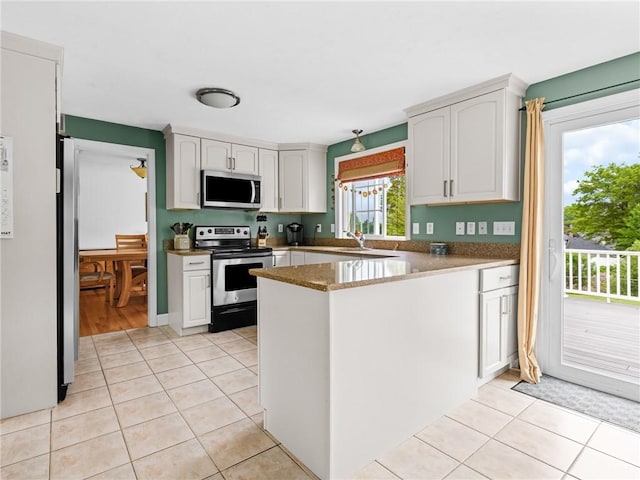 60 Broad St, Plainville, MA 02762 - kitchen with stainless steel appliances, a peninsula, light tile patterned flooring, and white cabinetry