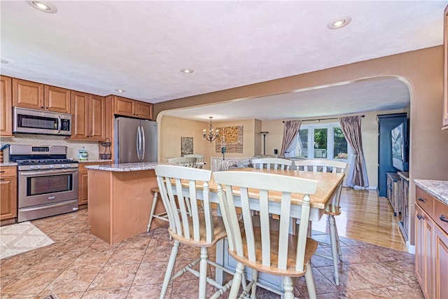 7 Lydia Ave, North Providence, RI 02904 - kitchen with stainless steel appliances, arched walkways, tasteful backsplash, recessed lighting, and brown cabinets