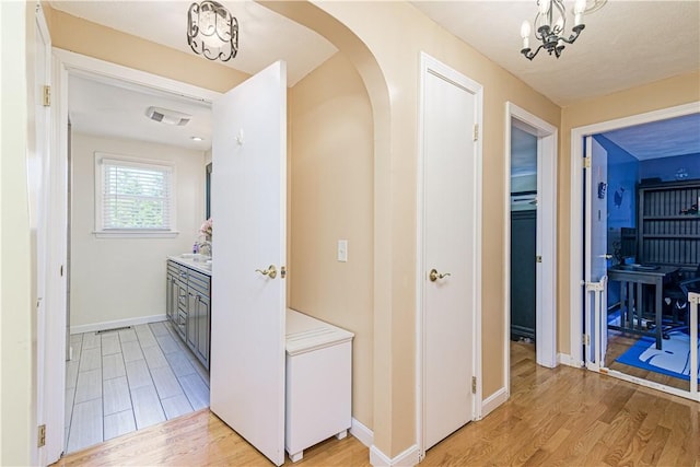 7 Lydia Ave, North Providence, RI 02904 - corridor with light wood-style floors, arched walkways, a sink, baseboards, and a chandelier