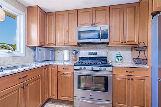7 Lydia Ave, North Providence, RI 02904 - kitchen featuring appliances with stainless steel finishes, a sink, brown cabinets, and decorative backsplash