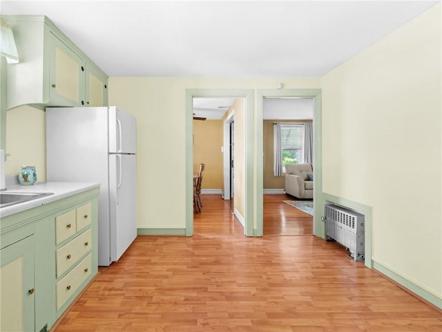 25 Community Rd, Warwick, RI 02889 - kitchen featuring green cabinets, radiator heating unit, freestanding refrigerator, light wood-style floors, and light countertops