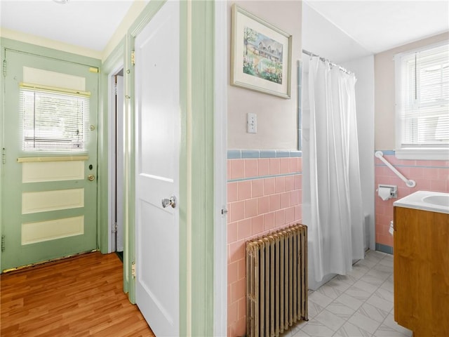 25 Community Rd, Warwick, RI 02889 - bathroom featuring radiator heating unit, healthy amount of natural light, tile walls, vanity, and shower / bath combination with curtain