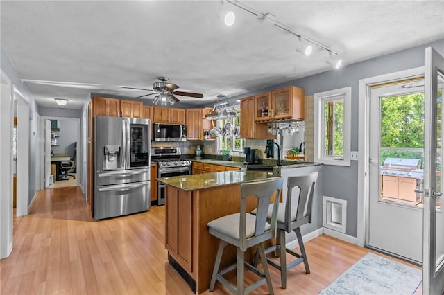 21 High Service Ave, North Providence, RI 02911 - kitchen featuring appliances with stainless steel finishes, brown cabinets, a peninsula, and decorative backsplash