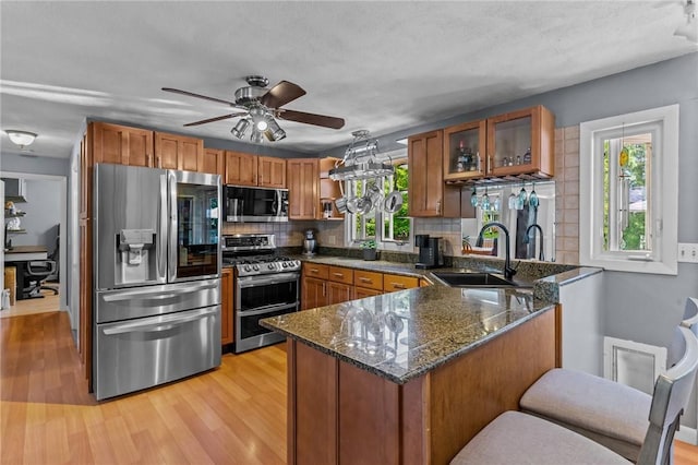 21 High Service Ave, North Providence, RI 02911 - kitchen with stainless steel appliances, a sink, a peninsula, and brown cabinetry