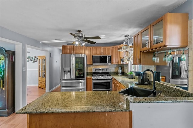 21 High Service Ave, North Providence, RI 02911 - kitchen with stainless steel appliances, a sink, light wood finished floors, brown cabinets, and dark stone countertops