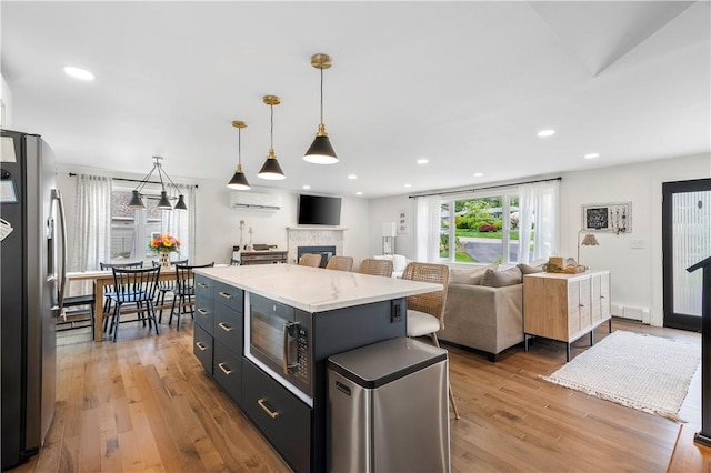 50 Maureen Dr, Smithfield, RI 02917 - kitchen featuring stainless steel fridge with ice dispenser, black microwave, a wall unit AC, light wood-type flooring, and a center island