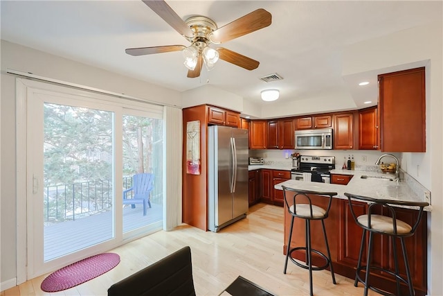 2970 Mendon Rd Unit 53, Cumberland, RI 02864 - kitchen featuring appliances with stainless steel finishes, a sink, a peninsula, a kitchen bar, and light wood-style flooring