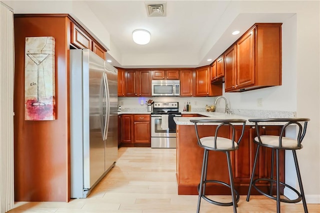 2970 Mendon Rd Unit 53, Cumberland, RI 02864 - kitchen featuring stainless steel appliances, a peninsula, light countertops, light wood finished floors, and a breakfast bar area