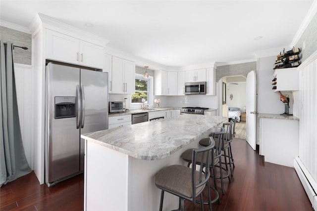 6 Humes Ave, Warwick, RI 02889 - kitchen featuring appliances with stainless steel finishes, baseboard heating, arched walkways, dark wood-style floors, and white cabinetry