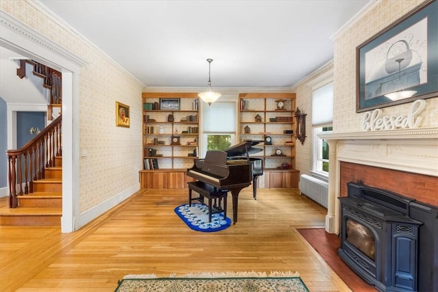 59 Woodland Rd, Woonsocket, RI 02895 - sitting room with wallpapered walls, radiator heating unit, a wood stove, wood finished floors, and stairway