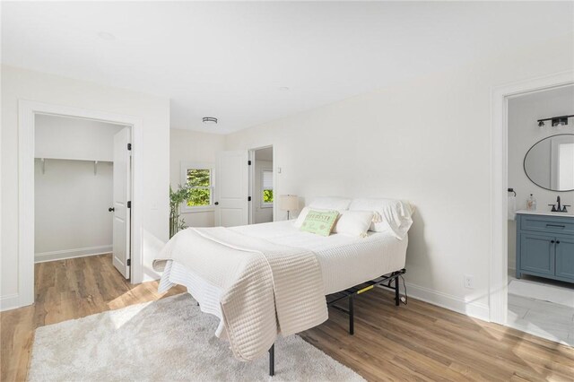 126 Weaver Hill Rd, West Greenwich, RI 02817 - bedroom with light wood-style floors, a sink, baseboards, a walk in closet, and ensuite bath