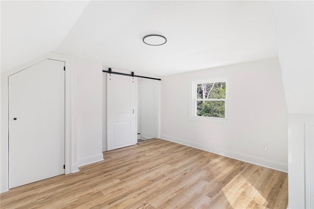 126 Weaver Hill Rd, West Greenwich, RI 02817 - unfurnished bedroom featuring a barn door, light wood-style flooring, and baseboards
