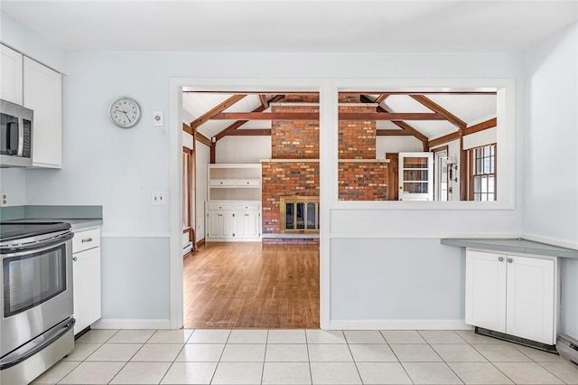 11 Crosswynds Dr, Narragansett, RI 02874 - kitchen with stainless steel appliances, white cabinets, baseboards, a fireplace, and light tile patterned floors